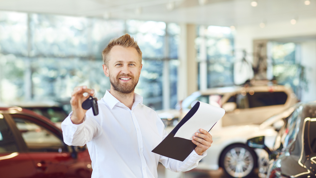 Fröhlicher Autohändler mit Schlüssel in der Hand, weil er der Kaufzurückhaltung beim Automobilkauf entgegenwirkt