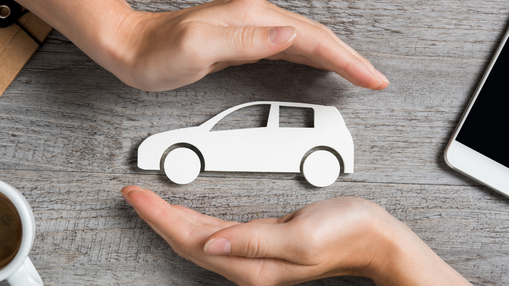 Hände umschließen ein symbolisches Auto wie eine Versicherung für den Wertverlust im Schadensfall