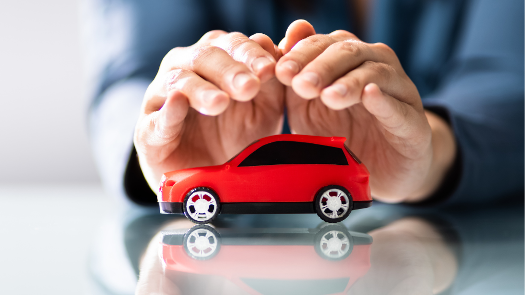 Autohändler schützt rotes Spielzeugauto mit seinen Händen. Wettbewerbsfähige Versicherungsprodukte für den Kfz-Handel